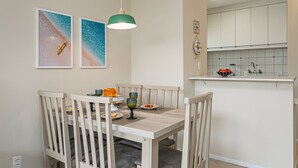Un coin repas avec une table et des chaises en bois, un luminaire suspendu et deux tableaux encadrés accrochés au mur.