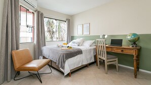 Une chambre à coucher avec un lit, un bureau, une chaise, un globe terrestre et une fenêtre avec des rideaux.