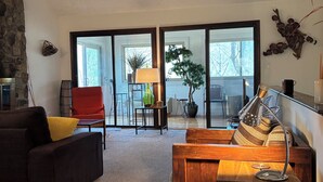 A living room with a sofa, a wooden coffee table, a red chair, and a potted plant. - Bent Tree Family 2BR - Hot Tub, Mountain View Deck, Pool, Golf, Lake & Fish (Jasper)