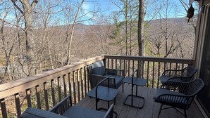 A wooden deck with outdoor furniture, a railing, and a view of trees and hills. - Bent Tree Family 2BR - Hot Tub, Mountain View Deck, Pool, Golf, Lake & Fish (Jasper)