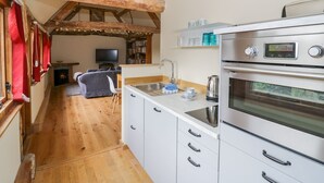 Eine kompakte Küche mit Einbauofen, Spüle und einer kleinen Essecke mit einer Couch.