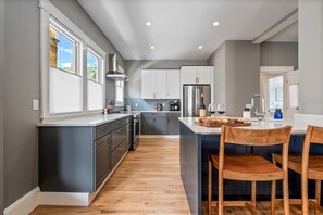A modern kitchen with grey cabinets, a stainless steel refrigerator, and a wooden dining table. - Urban Ease/By Downtown/Parking (Portland)