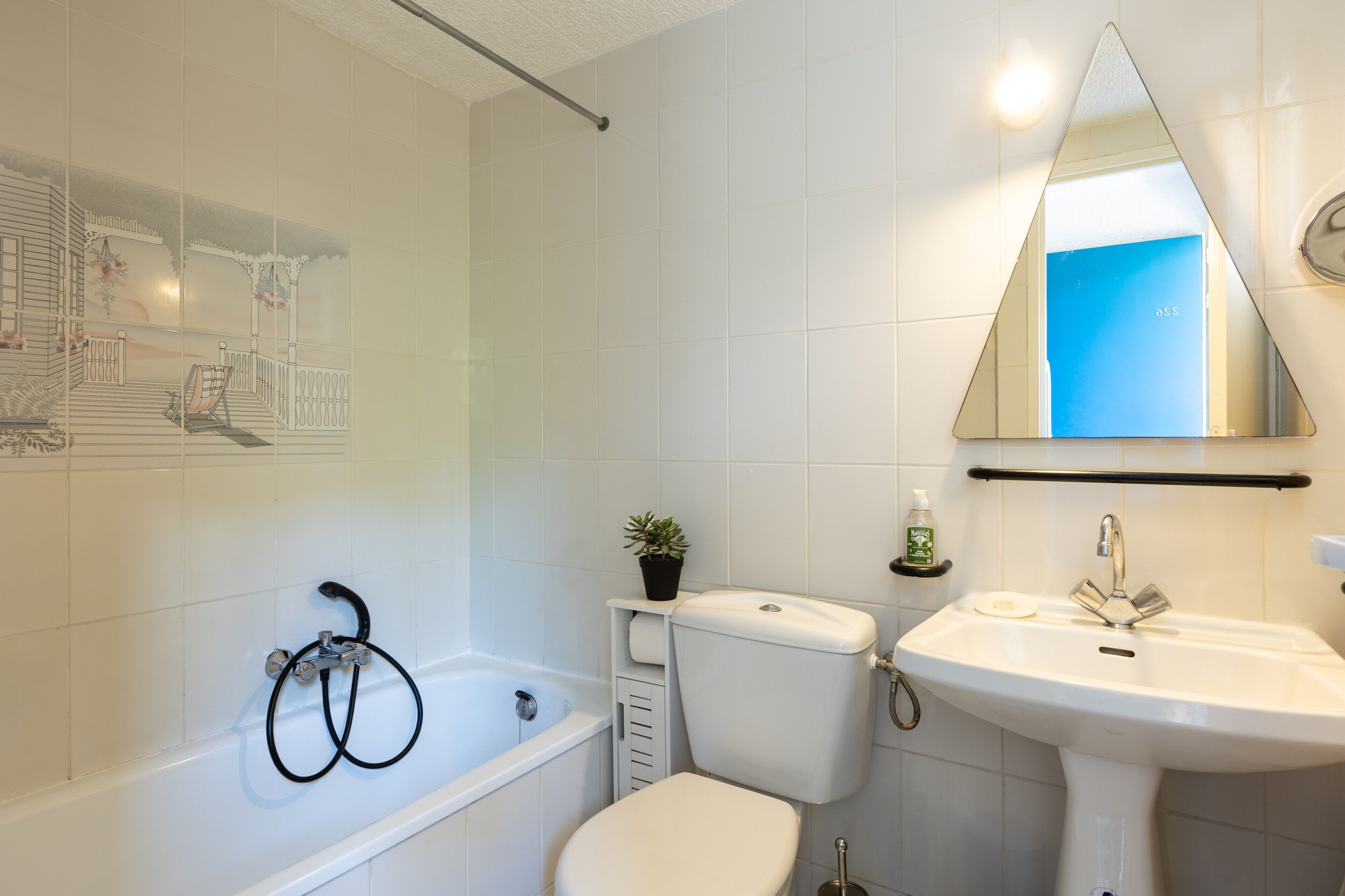 Une salle de bain équipée d’une baignoire, de toilettes, d’un lavabo et d’un miroir.