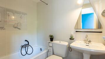 Une salle de bain équipée d’une baignoire, de toilettes, d’un lavabo et d’un miroir.