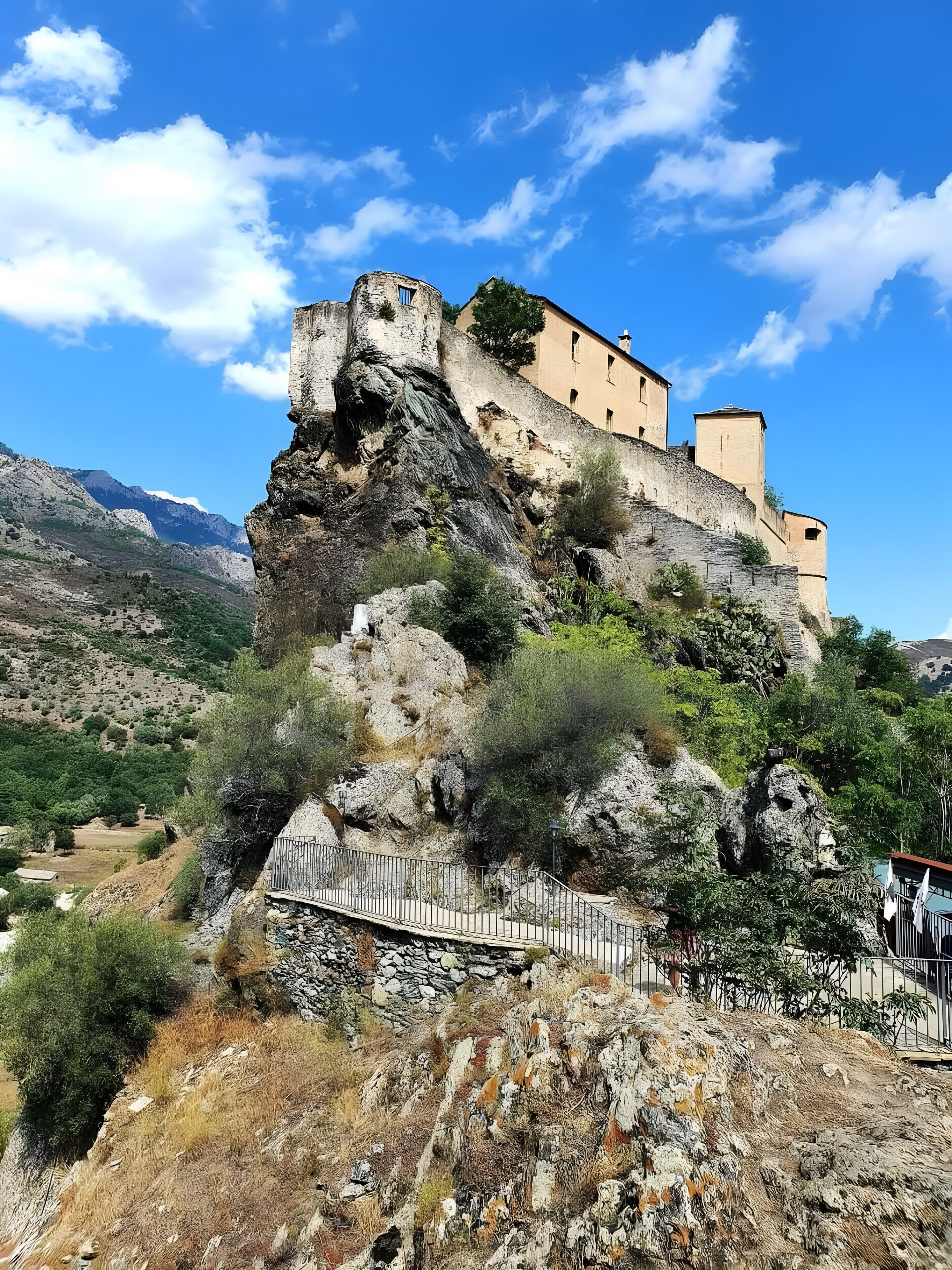 Un castillo de piedra histórico enclavado en un acantilado rocoso, con cielo despejado.