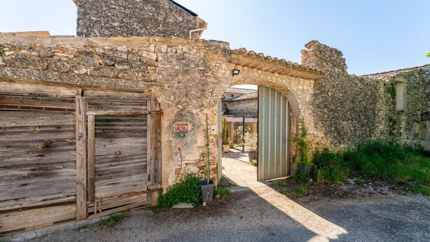 Un edificio de piedra con puerta de madera, un pequeño arco y una puerta verde.