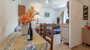 Un comedor con una mesa dispuesta para dos, un florero con flores, una lámpara y un cuadro en la pared.