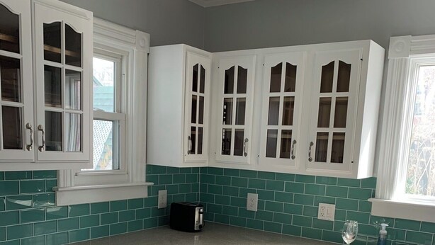 Cocina con gabinetes blancos, lavavajillas y ventana con vistas.