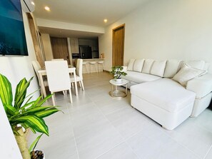 A modern living room with a white sofa, a dining area with chairs, a small round table, and a kitchen in the background. - Oceanfront Residence with Access to the Exclusive Beach Club (Cartagena)