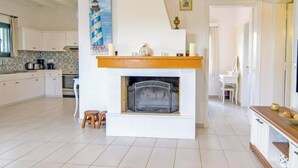 Una cucina moderna con camino, zona pranzo e televisore su un supporto in legno.