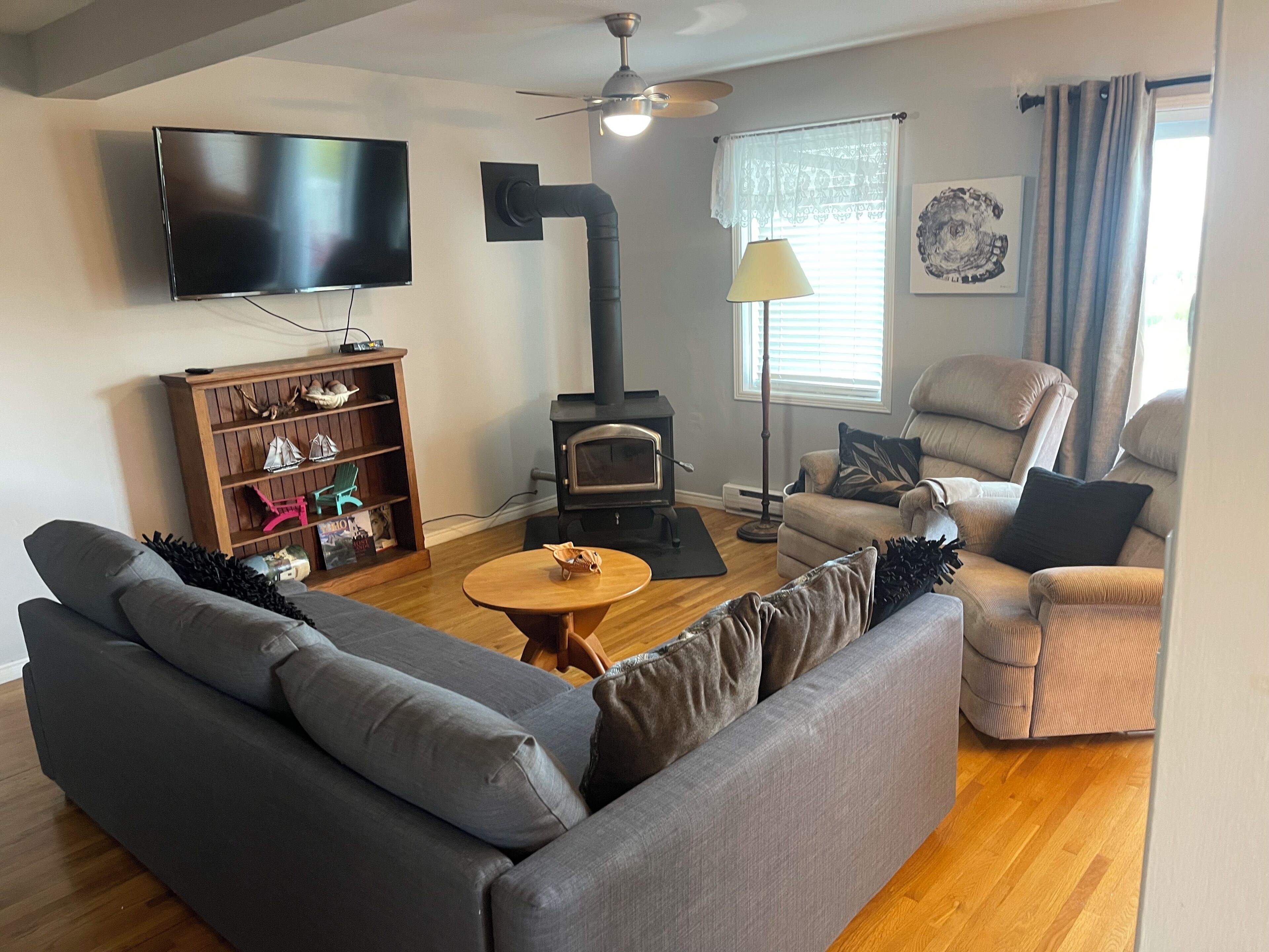 A living room with a sofa, armchair, TV, fireplace, and bookshelf.
