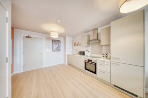 A modern kitchen with white cabinetry, a built-in oven, and a microwave.