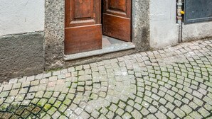 Een houten dubbele deur met een stenen boog, een huisnummer en een technische kast op een kinderafdeling.