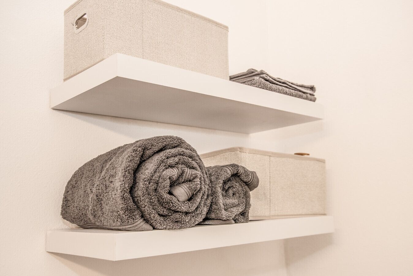 Trois étagères blanches, avec des serviettes pliées et une boîte.