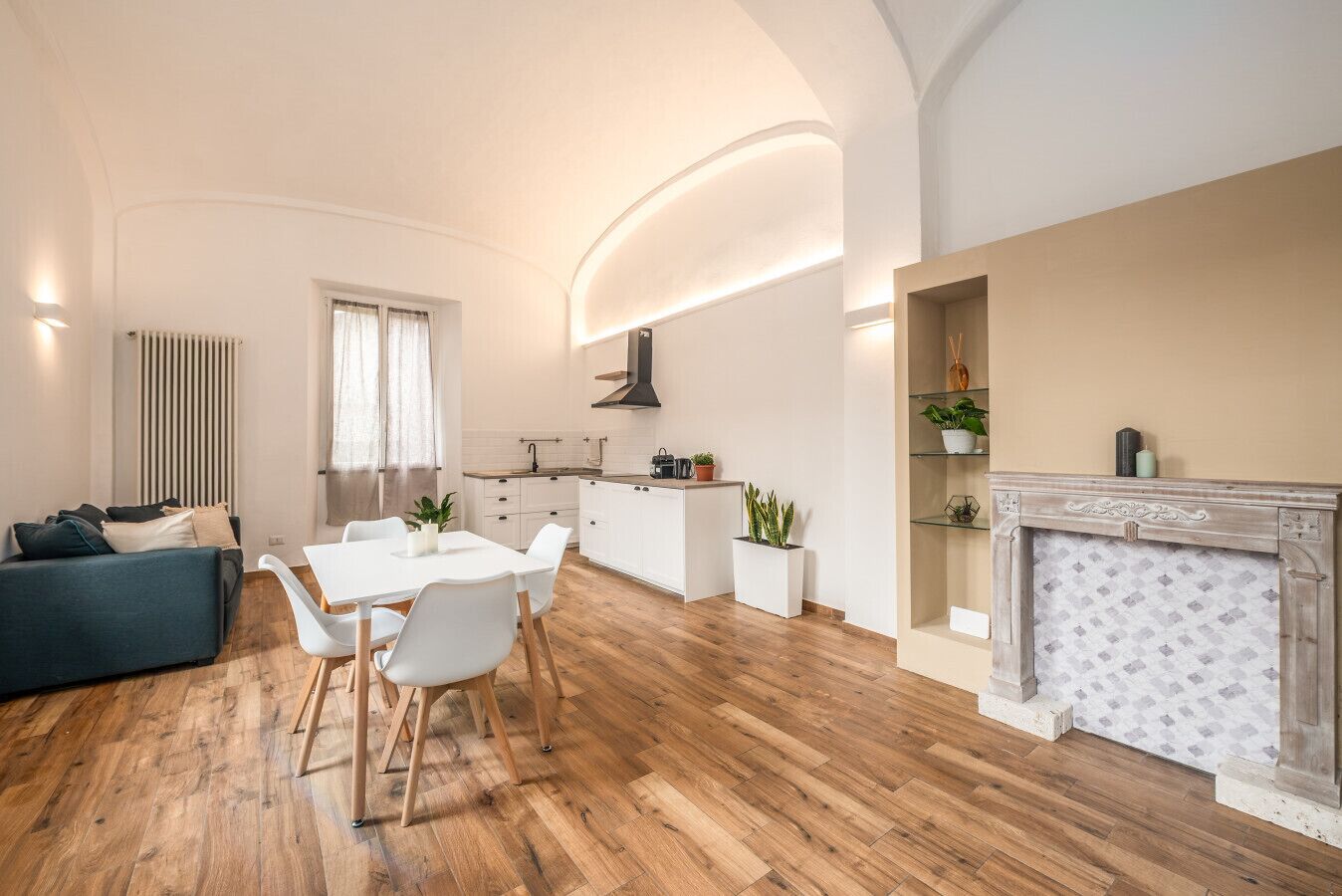 Ein modernes Wohnzimmer mit Essbereich, einer Küche und einem Kamin.