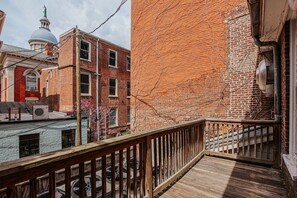 Een houten balkon met een leuning, een bakstenen gebouw en een koepelstructuur op de achtergrond.