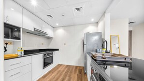 Ett modernt kök med vita skåp, ett kylskåp i rostfritt stål, en inbyggd ugn och en tvättmaskin.