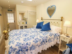 Een slaapkamer met een bed, nachtkastjes, een spiegel en een hartvormige spiegel aan de muur.