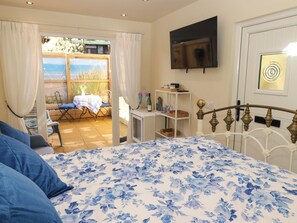 A bedroom with a bed, a TV, a window, and a view of the outdoors. - Sea Folly (Porthcawl)