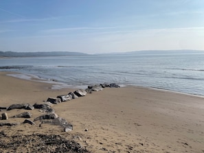 Een strand met een rotsachtige kustlijn en rustig water.