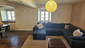 Una sala de estar con un sofá modular, una mesa de centro de madera, un comedor con mesa y sillas, y un ventanal con vistas.