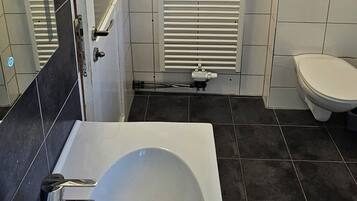 Ein Badezimmer mit Waschbecken, Spiegel, Handtuchhalter, Toilette und Heizkörper.