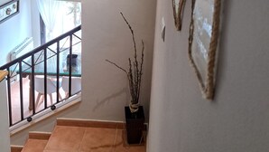 Una escalera que lleva a una plataforma con vistas al exterior, barandilla y un adorno fijado a la pared.