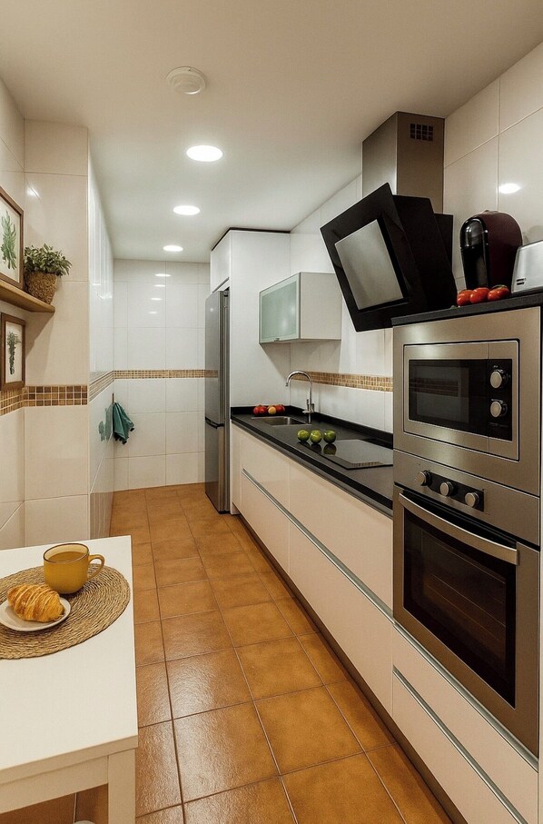 A kitchen with a microwave, oven, and a sink.
