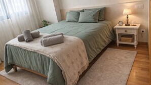 Un dormitorio con cama, mesita de noche, lámpara y una lámpara colgante.