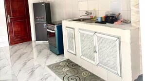 A kitchen with a refrigerator, stove, and cabinets. - Résidence au 2 Plateaux 3 Chambres (Abidjan)