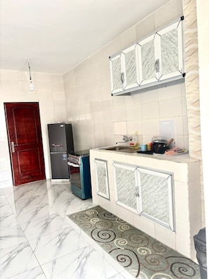 Una cocina con armarios blancos, un refrigerador y una estufa.