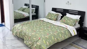 A bedroom with a bed, a mirror, and a nightstand. - Résidence au 2 Plateaux 3 Chambres (Abidjan)