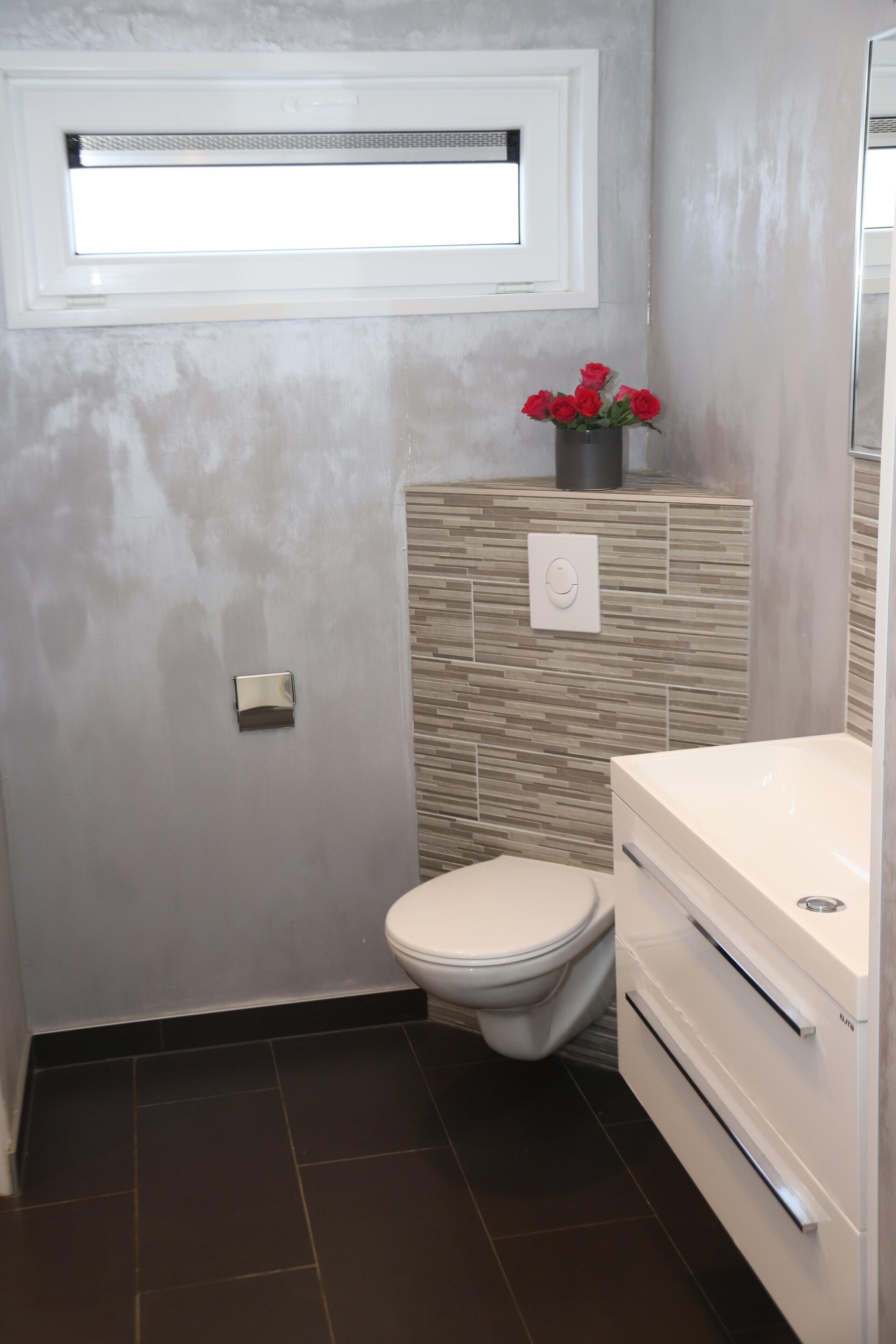 A bathroom with a toilet, a sink, and a wall-mounted light fixture.
