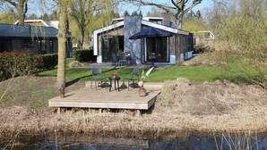 A modern house with a deck, outdoor furniture, and a pond. - Chalet in Biddinghuizen, Pool Facilities (Biddinghuizen)