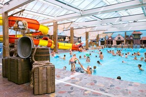 Une piscine intérieure dotée de plusieurs toboggans et d’un toit en verre.