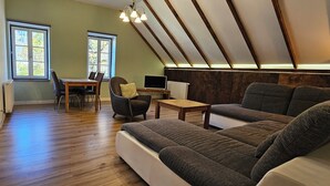 A loft-style room with a dining area, seating, and a TV.
