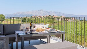 A balcony with a table set for dining, overlooking a mountainous landscape.