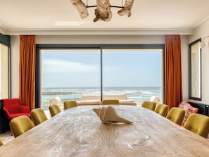 A conference room with a large table, multiple chairs, and a view of the ocean.
