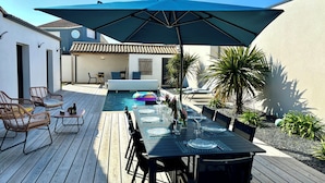 A wooden deck with a pool, outdoor seating, and a table set for dining.
