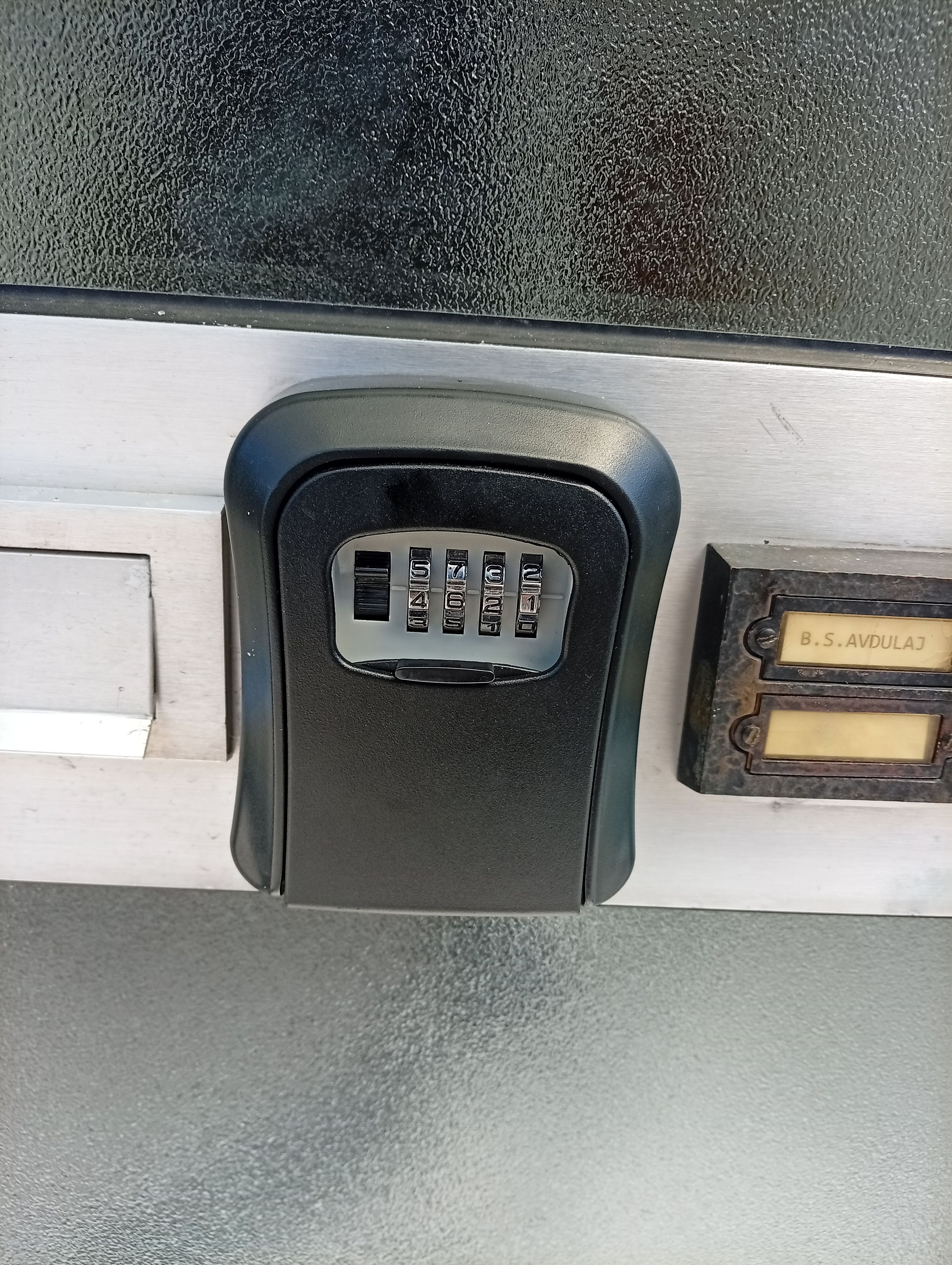 A vehicle's interior with a black panel featuring a keypad and a metal plate with text.