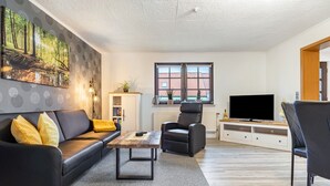 A modern living room with a sofa, armchair, coffee table, and a television.