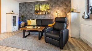 A modern living room with a sofa, a recliner, a coffee table, and a painting on the wall.