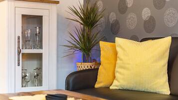 A living room with a sofa, a cabinet with glass doors, and a potted plant.