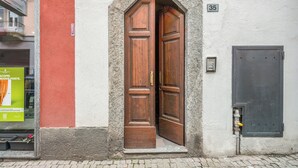 Una porta in legno con stipite in pietra, una targa con il numero '35' e una piccola finestra con un manifesto.