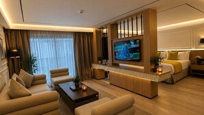 A modern living room with a flat-screen TV, sofas, a coffee table, and a dining area.