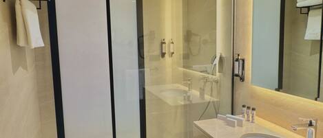 A modern bathroom with a glass shower enclosure, a large mirror, and a double sink vanity.