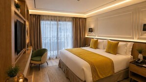 A modern hotel room with a large bed, a television, a desk, and a chair.