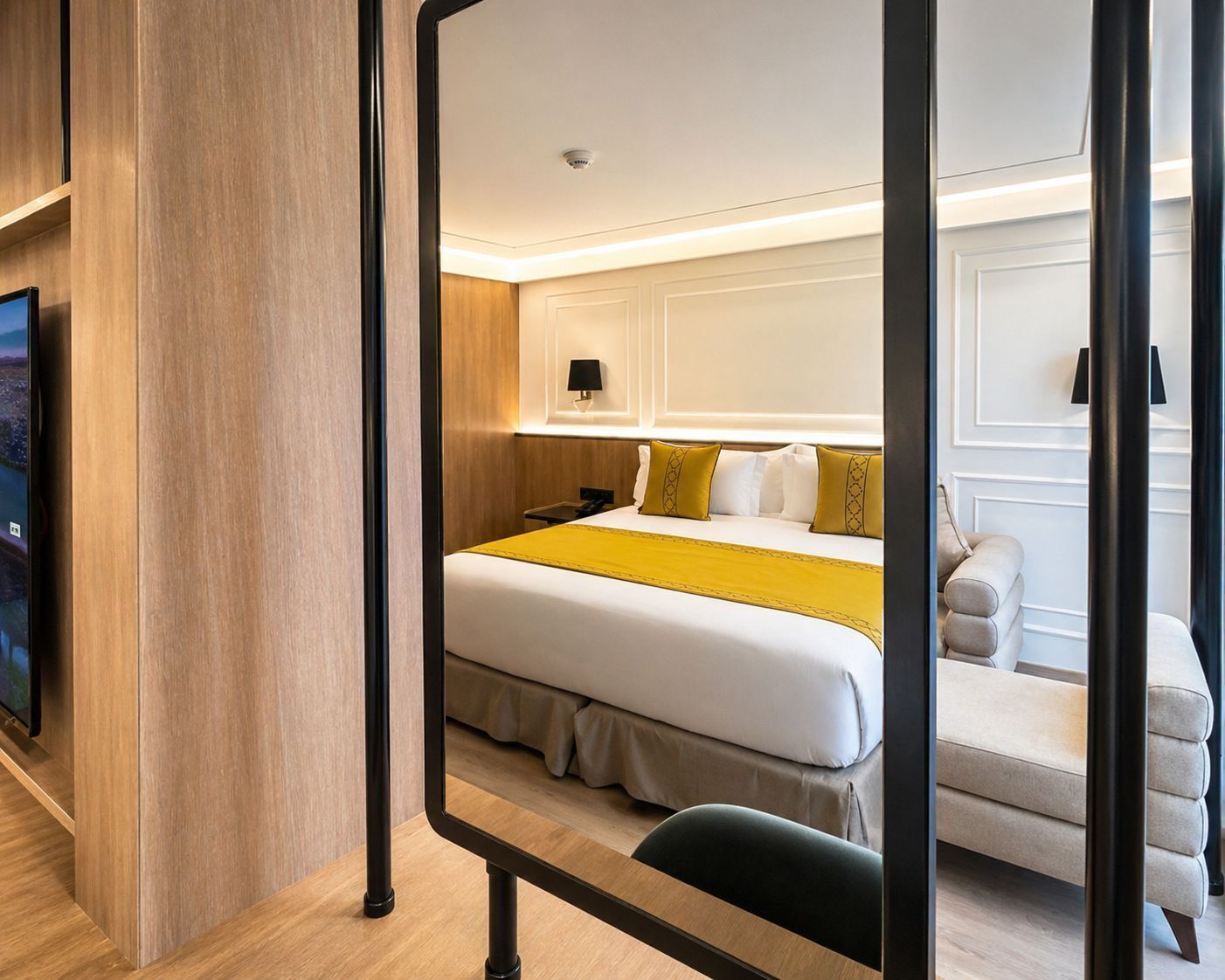 A hotel room with a bed, bedside table, lamp, and a television.