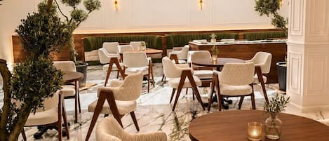 Un vestíbulo de hotel con una zona de estar, suelo de mármol y plantas en macetas.