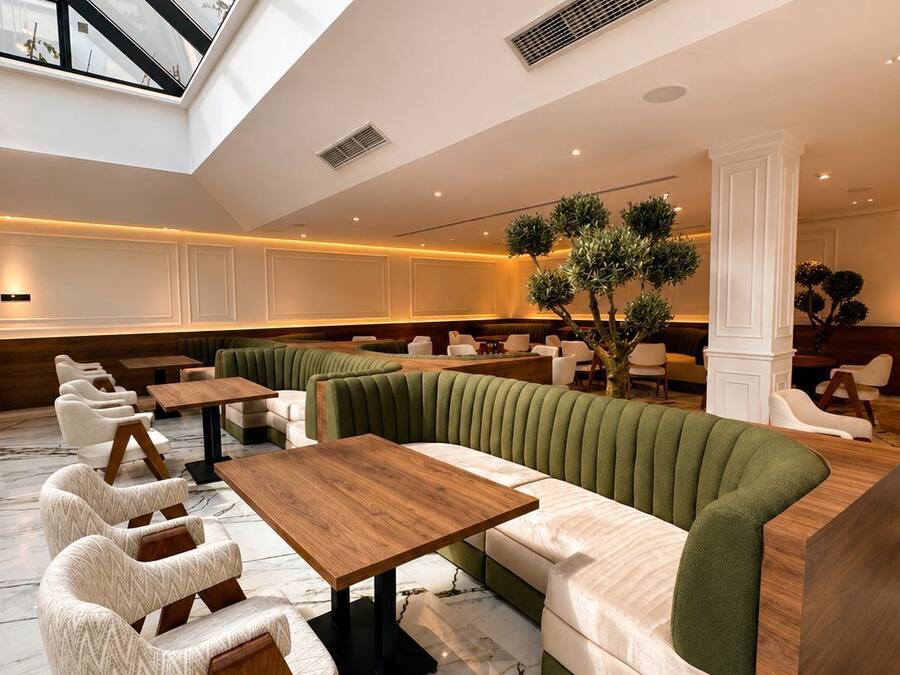 A modern interior with a high ceiling, marble flooring, and a seating area with green upholstered sofas and white armchairs.